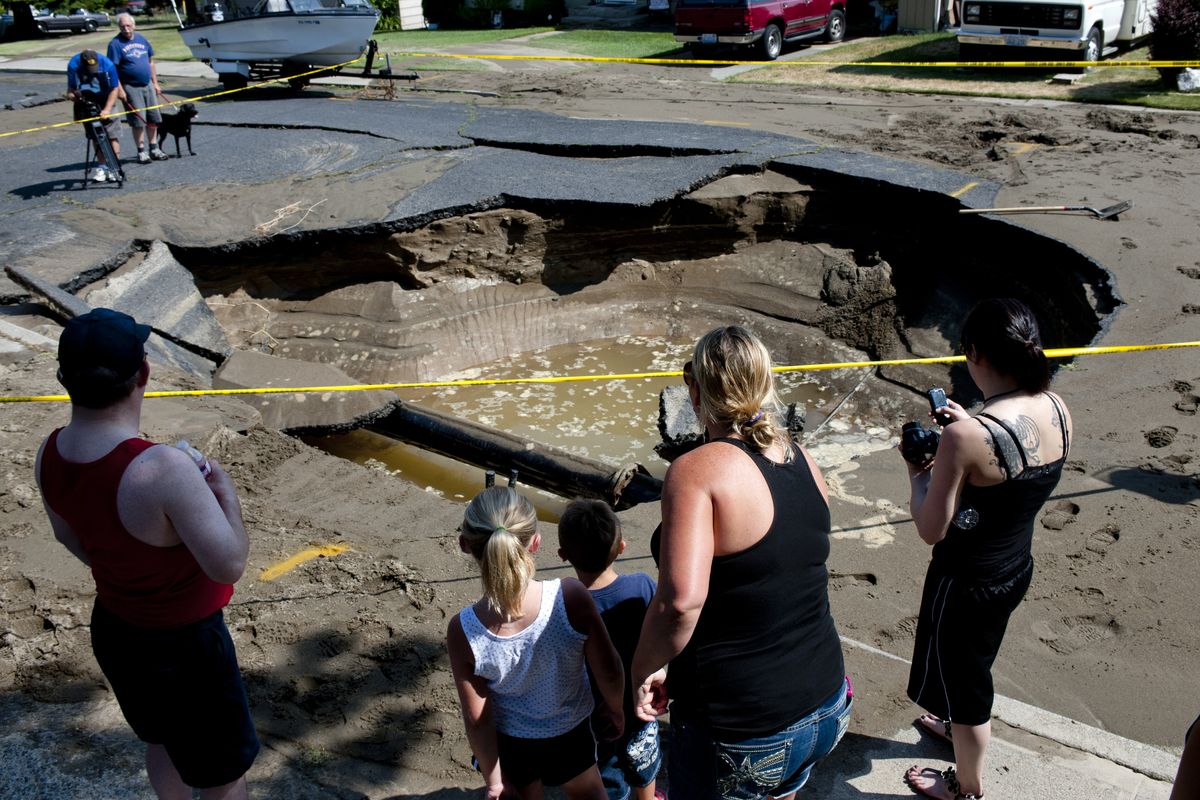 Residents and members of the media gather around the area where a water main broke on Monday at West Houston Avenue in Spokane. (Tyler Tjomsland)