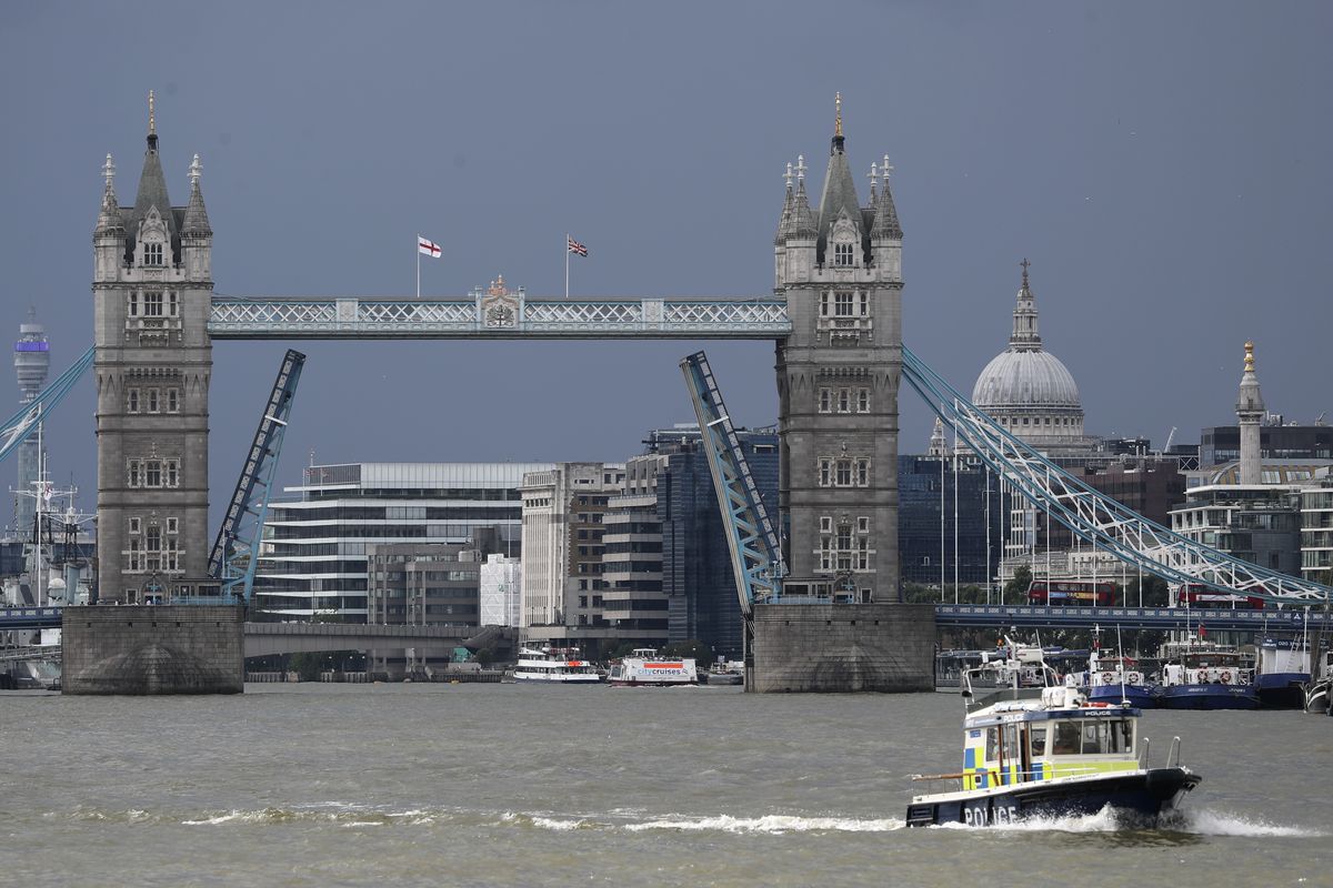 A police boat sails down the River Thames in London, Monday Aug. 9, 2021 in front of Tower Bridge that is stuck in the fully open position due to a technical fault.  (Tony Hicks)