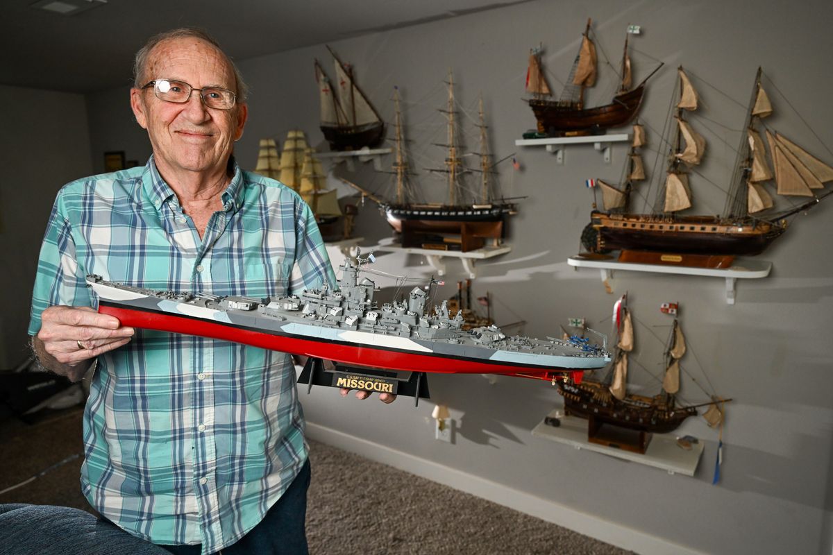 Bill Widrig holds a detailed plastic model of the USS Missouri and stands next to the wall of ship models he has built and displays in the basement of his North Side home, shown March 28. His finished models are from a mix of plastic and wood modeling kits.  (Jesse Tinsley/THE SPOKESMAN-REVIEW)