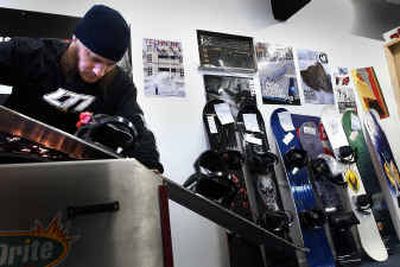 
L77 snowboard shop tech Corey Kissell grinds the chunks and scrapes off a board. 
 (Brian Plonka / The Spokesman-Review)