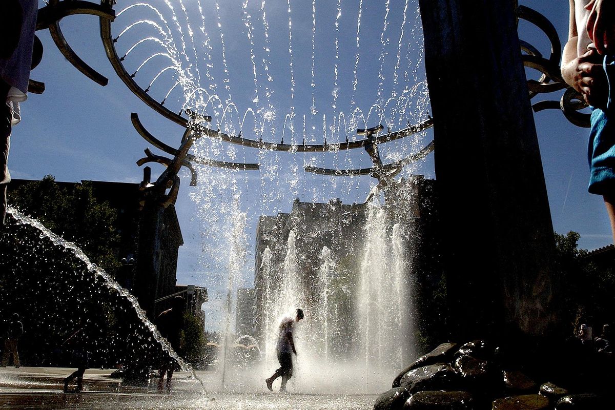In this Sept. 1, 2005 photo, a visitor the the new 60 foot wide water fountain at Riverfront Park in downtown Spokane is doused with some 3,500 gallons of water per minute via 150 jets that spray 35 feet into the air. (Spokesman-Review)