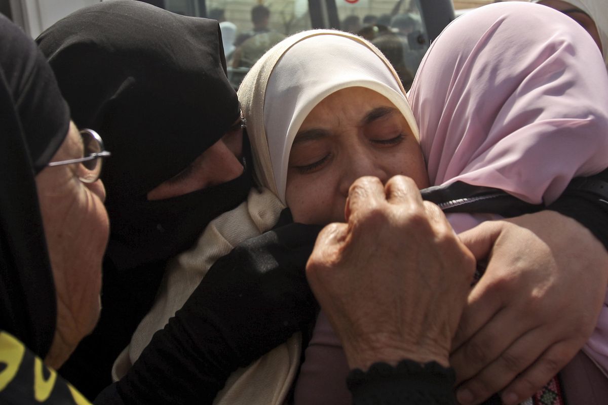 Palestinian women hug a newly released prisoner after crossing the Beituniya checkpoint to the West Bank city of Ramallah on Friday.  (Associated Press / The Spokesman-Review)