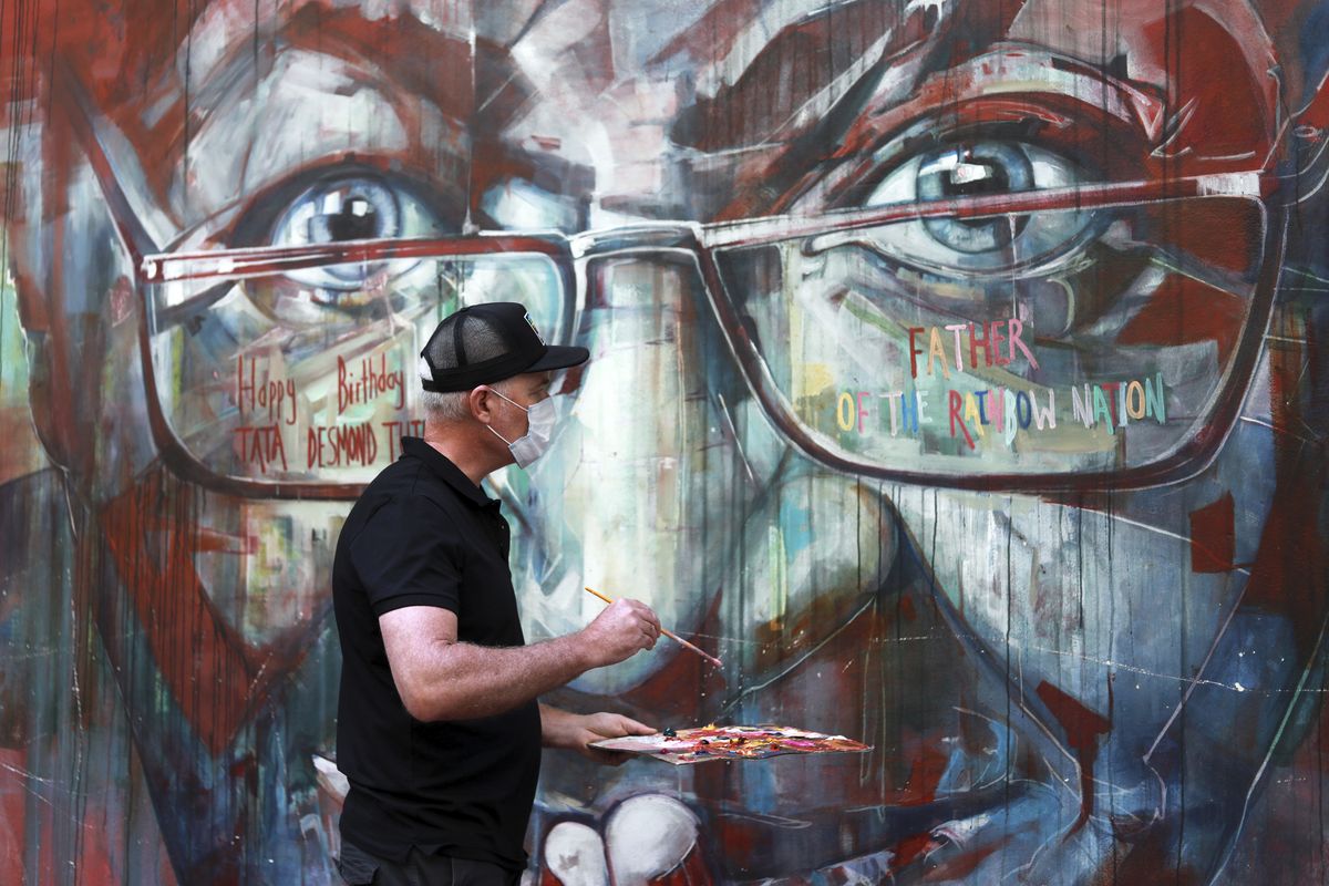A wall mural, depicting Anglican Archbishop Emeritus, Desmond Tutu, is restored by the artist Brian Rolfe after it was defaced, in Cape Town, South Africa Thursday Oct. 7, 2021. As South Africa
