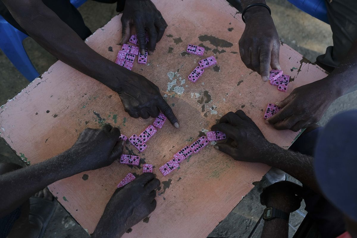 Men play a game of dominoes in their spare time in the Batey La Lima community, in La Romana, Dominican Republic, Wednesday, Nov. 17, 2021. Human rights activists say an increasing mistreatment of the country’s Haitians coincided with the rise of Luis Abinader, who took office as president in August 2020.  (Matias Delacroix)