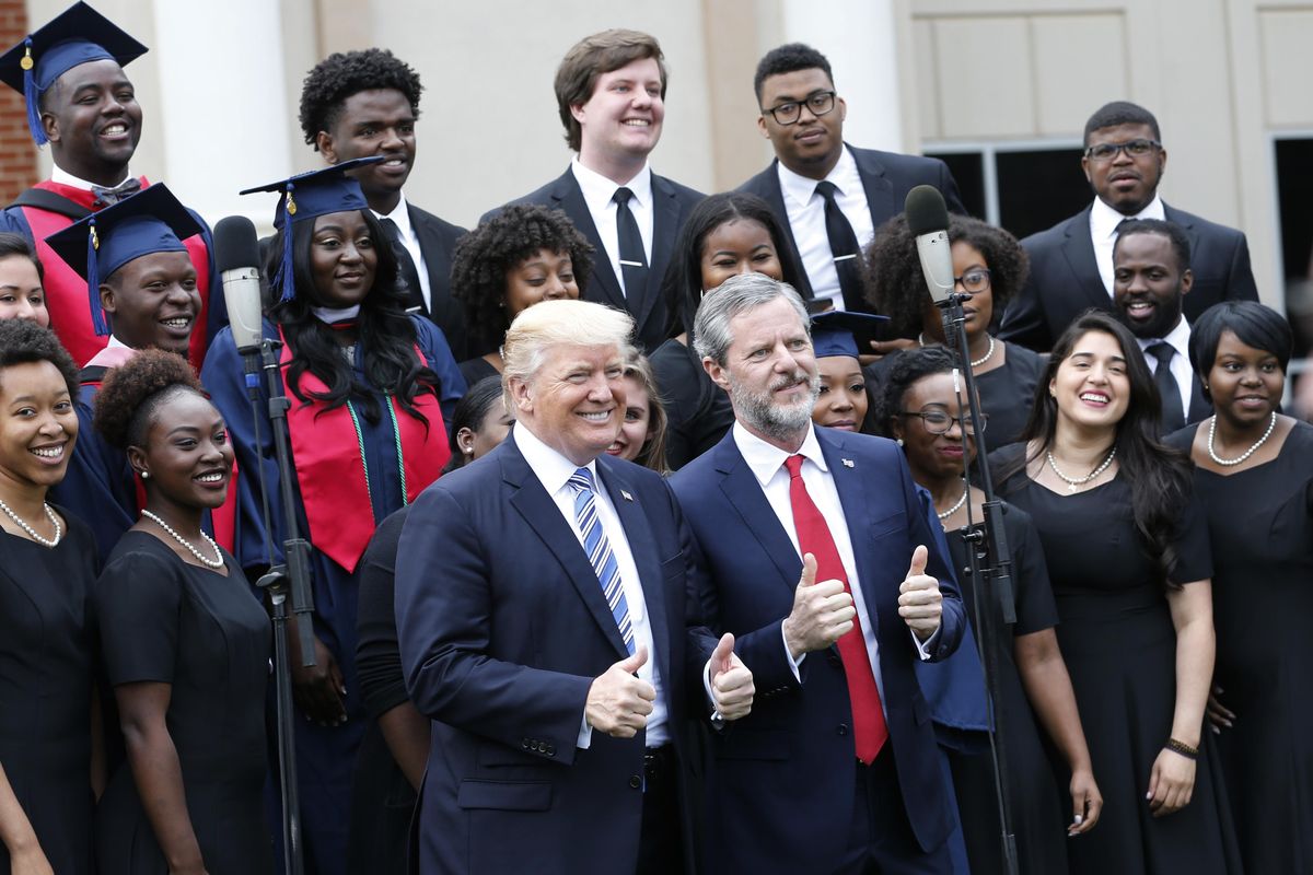 President Donald Trump poses with Liberty University President Jerry Falwell Jr., center right, in front of a choir during  commencement ceremonies at the school in Lynchburg, Va., Saturday, May 13, 2017. (Steve Helber / Associated Press)