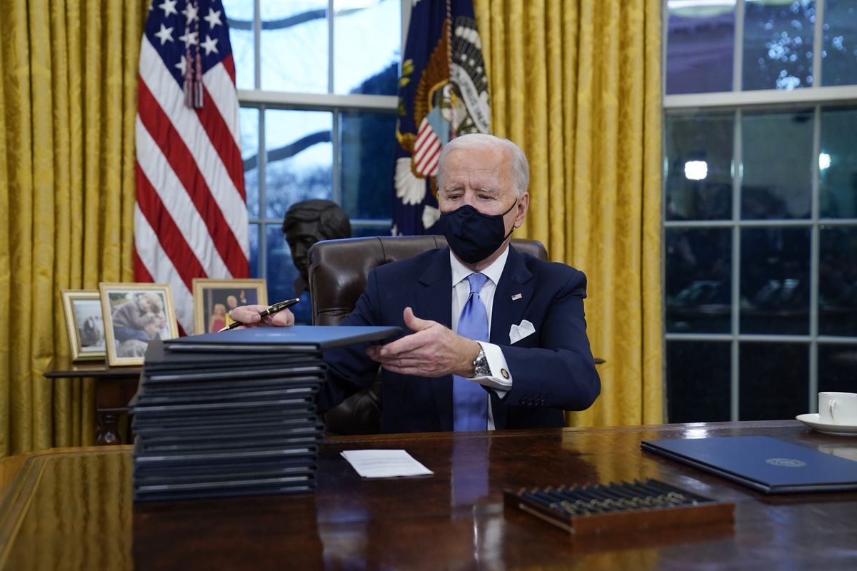 President Joe Biden signs his first executive orders in the Oval Office of the White House on Wednesday, Jan. 20, 2021, in Washington.   (Evan Vucci)