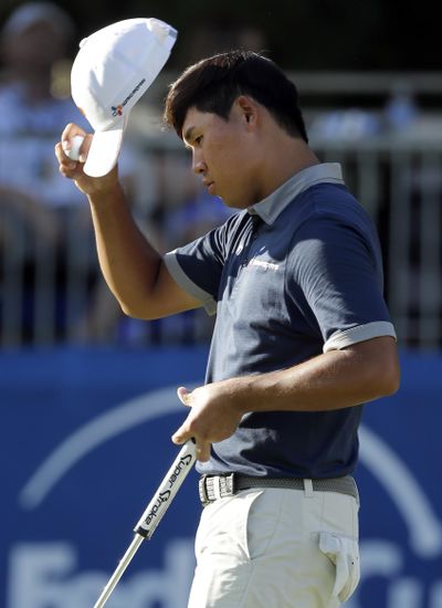 Si Woo Kim tips his hat to the crowd after finishing the 18th hole. (Chuck Burton / Associated Press)