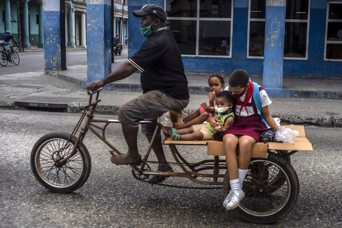 A man transports children on his tricycle, in Havana, Cuba, Friday, Jan 8, 2021, amid the new coronavirus pandemic.  (Ramon Espinosa)