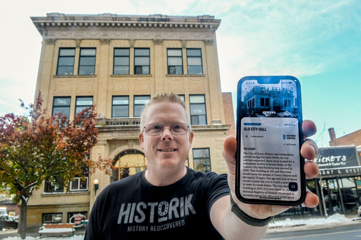 Chris Whalen, founder of Historik, an immersive app for historic landmarks, displays information available about old City Hall while standing in front of the building built in 1908 in Coeur d’Alene.  (KATHY PLONKA/THE SPOKESMAN-REVIE)