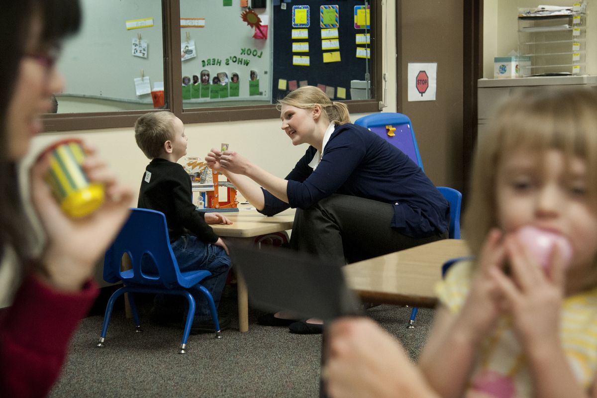 Graduate student Lauren Burrows, back right, works with Sage Fast, 4, in Eastern Washington University’s autism early learning center as part of the Domino Project on Jan. 23 in Cheney. Graduate student Ming-Yeh Hsieh, foreground left, helps Abigail Green, 4, to handle drinking cups.