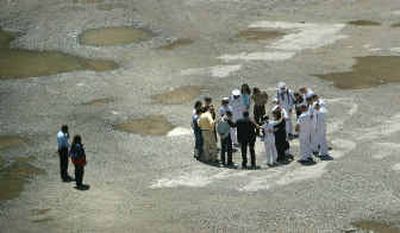 
Port Authority security staff, left, watch as a small prayer group including sailors, Marines and representatives of Sept. 11 families gather at ground zero at the World Trade Center site in New York on Friday. They prayed for the victims and for military men and women who have fought in Afghanistan and in Iraq. 
 (Associated Press / The Spokesman-Review)