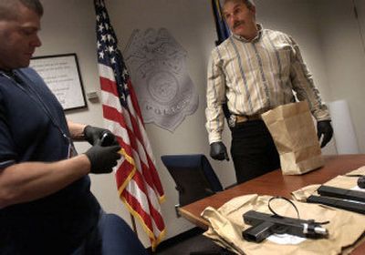 
After a press conference Monday afternoon, Spokane police Officer Larry Saunders, right, and Officer Michael Roberge prepare to put weapons back into evidence bags. The weapons, a semiautomatic handgun and a semiautomatic machine pistol, were seized when a confirmed gang member was arrested. 
 (Holly Pickett / The Spokesman-Review)