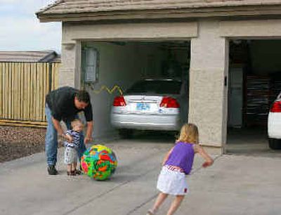 
In this photo provided by FuelMaker Corp., Dan Baker plays with his two children at his Chandler, Ariz. home. In his garage is a natural gas-powered Honda Civic GX with Phill, a home-refueling appliance. 
 (Associated Press / The Spokesman-Review)