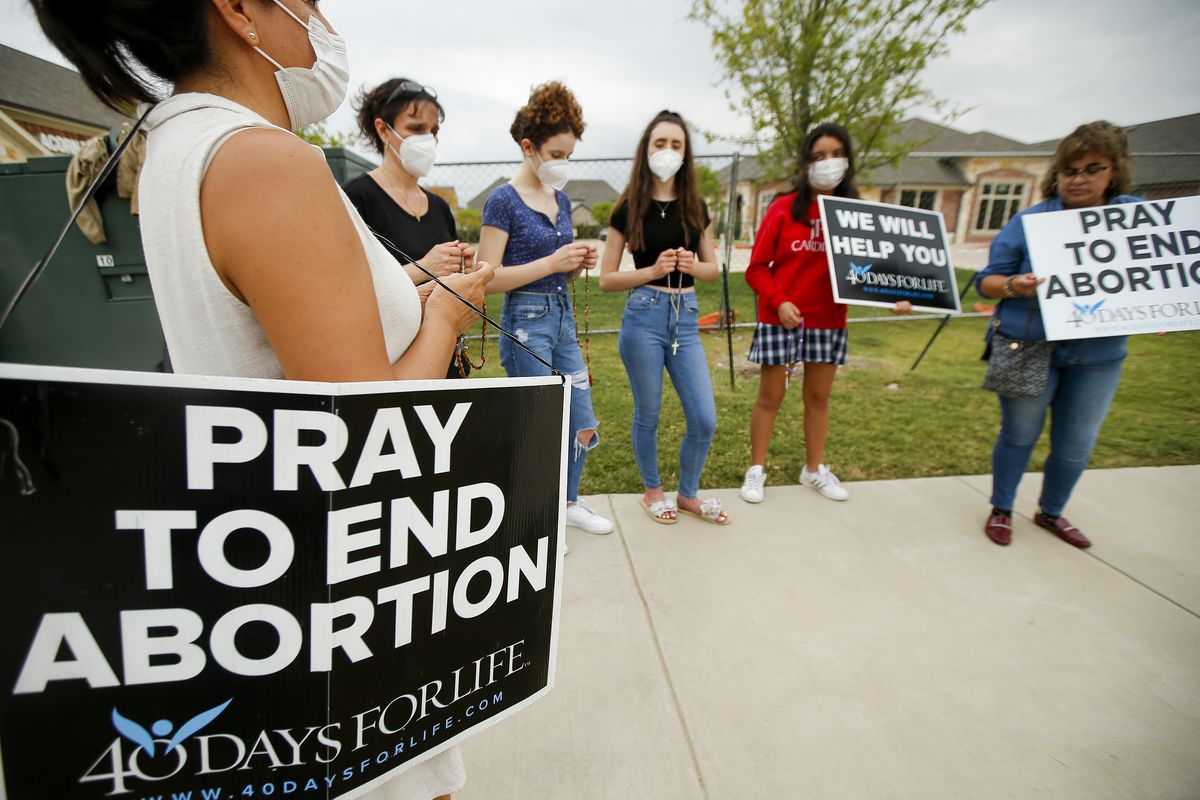 Anti-abortion demonstrators pray and protest outside of a Whole Women