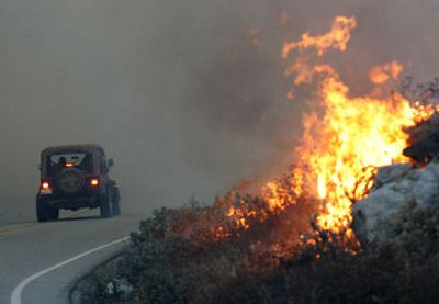 
A car attempts to drive past the wildfire on state Route 243 near Banning, Calif., on Thursday. Four firefighters were killed battling the blaze that officials say was deliberately set. 
 (Associated Press / The Spokesman-Review)