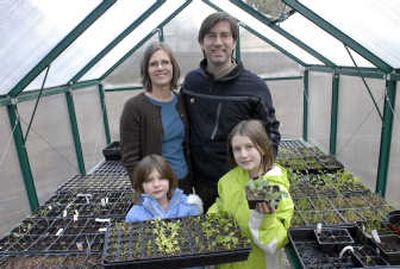 
Craig and Nancy Goodwin stand with their kids, Lily and Noel, in the family's backyard greenhouse. Lily, 6, shows off lettuce, tomato and onion starts, while Noel, 8, displays a cabbage start. Below: Among the food in the Goodwin pantry: from left, Silvana Meats Orange Chipotle Sauce (a gift from Western Washington), Tullia's Pasta Sauce, Christ Kitchen Bean Soup and Lighthouse Carmel Dip. 
 (J. Bart Rayniak photos / The Spokesman-Review)