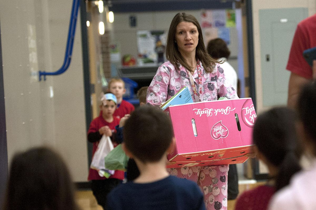 Kindergarten teacher Jennifer Snider carries donated items into an  assembly at Prairie View Elementary in Spokane on Wednesday, Dec. 20, 2017. The school held a fundraiser for the Vanessa Behan Crisis Nursery. (Kathy Plonka / The Spokesman-Review)