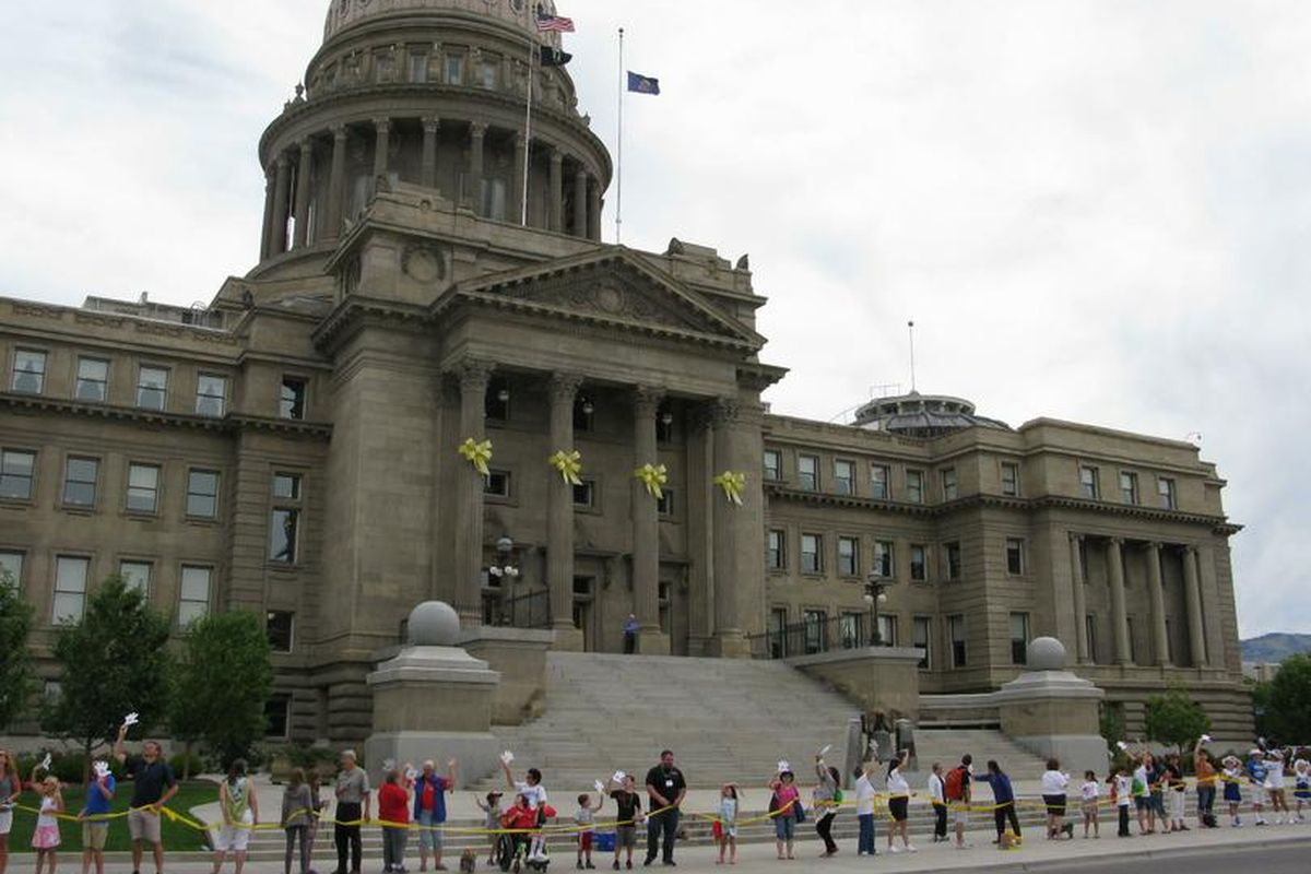Hundreds of people stretch a yellow ribbon around Idaho