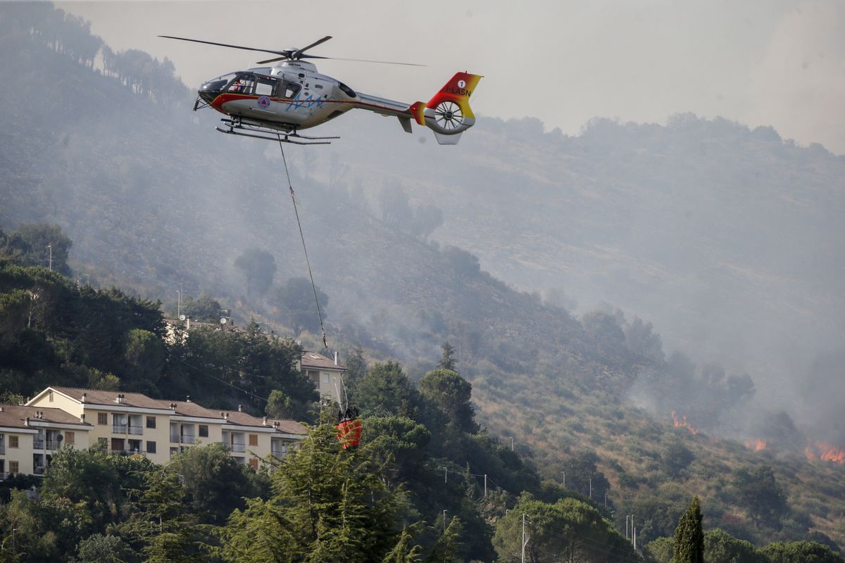 Emergency staff fights a fire on Castillo mountain park near Tivoli a few miles from Rome, Italy, Friday, Aug. 13, 2021. Intense heat baking Italy pushed northward towards the popular tourist destination of Florence Friday while wildfires charred the country