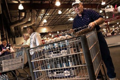 
Alan Berg buys two cases of bottled water at Costco on Friday after he was alerted that the water in his house, located in Water District 3, was contaminated by E. coli. 
 (Photos by Jed Conklin/ / The Spokesman-Review)