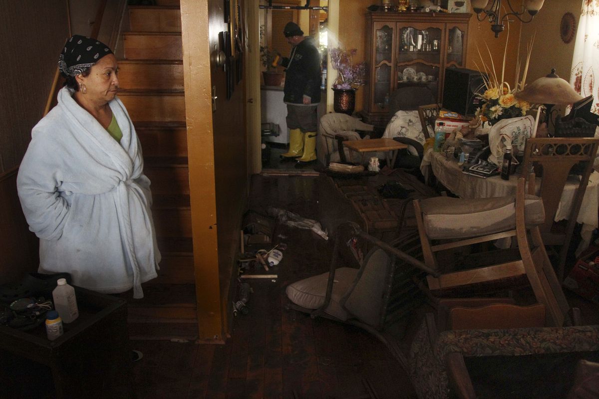 Virgen Perez, left, and her husband Nelson Rodriguez, center, look around their home which was flooded by Storm Sandy in Atlantic City, N.J. on Tuesday, Oct. 30, 2012. Their family stayed on the second floor of their home during the storm. (Seth Wenig / Associated Press)