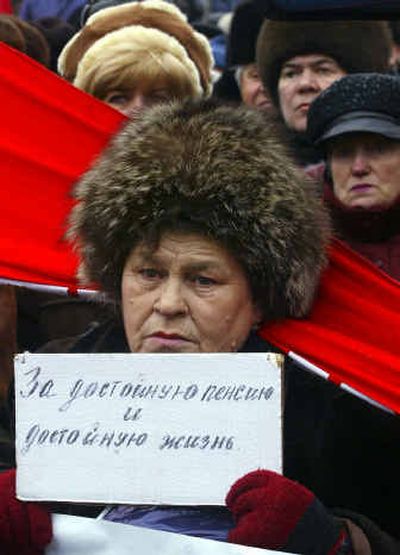 
A woman holds a placard, which reads: 