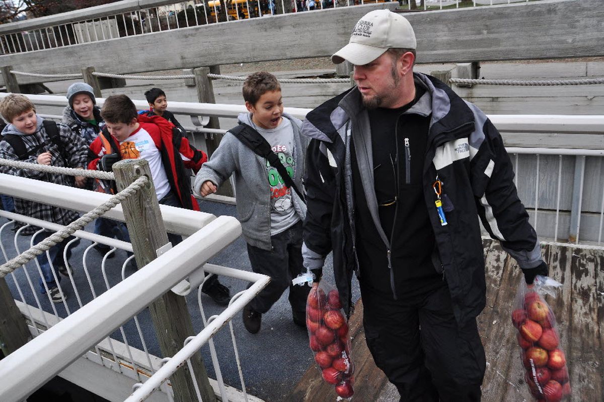 Chris Bachman, director of the Sierra Club Inner City Outings program in Spokane, leads a group of kids 8-12 years old to a cruise boat at the Coeur d