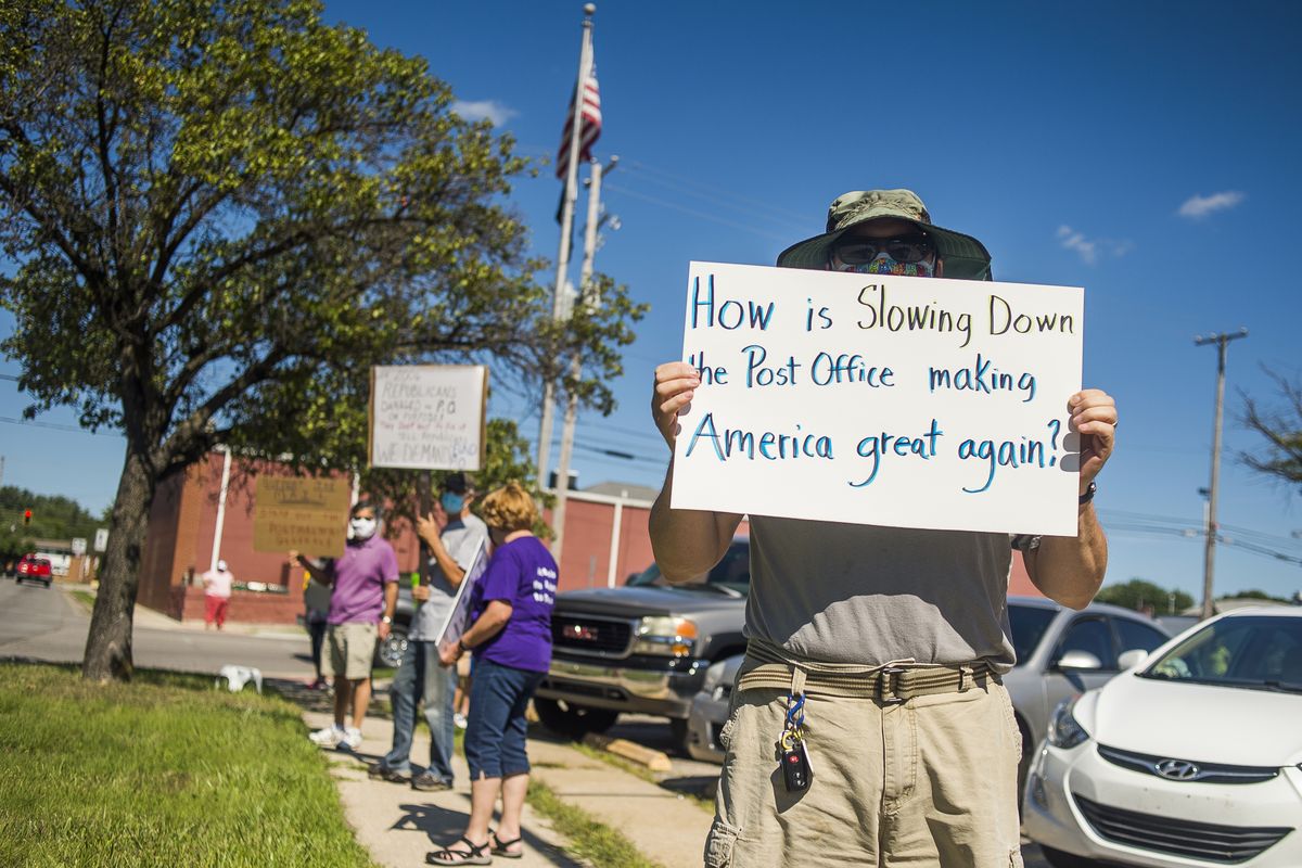 Eric Severson holds a sign Tuesday as a few dozen people gather in front of the United States Post Office on Rodd Street in Midland, Mich., to protest recent changes to the U.S. Postal Service under new Postmaster General Louis DeJoy.  (Katy Kildee)