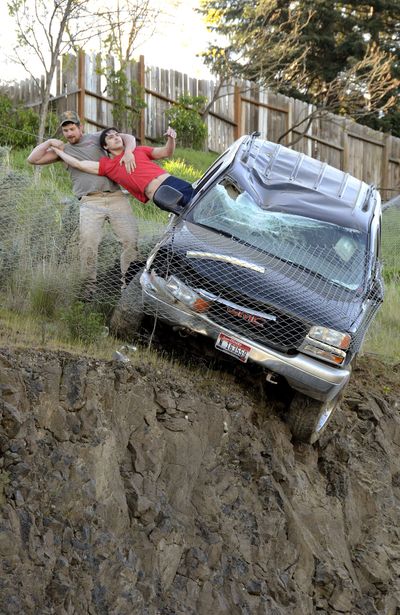 On the fence: Jason Warnock, left, pulls Mathew Sitko to safety from an SUV stopped by a chain link fence just short of a 30-foot vertical drop onto Bryden Canyon Road on Wednesday in Lewiston. The 23-year-old driver suffered minor injuries and was taken to a hospital, according to authorities. (Barry Kough)