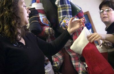 
Union Gospel Mission employees Jenny Gibbs, left, and Dorothy Vogel hang donated stockings stuffed with presents Wednesday afternoon in preparation for Christmas. 
 (Holly Pickett / The Spokesman-Review)