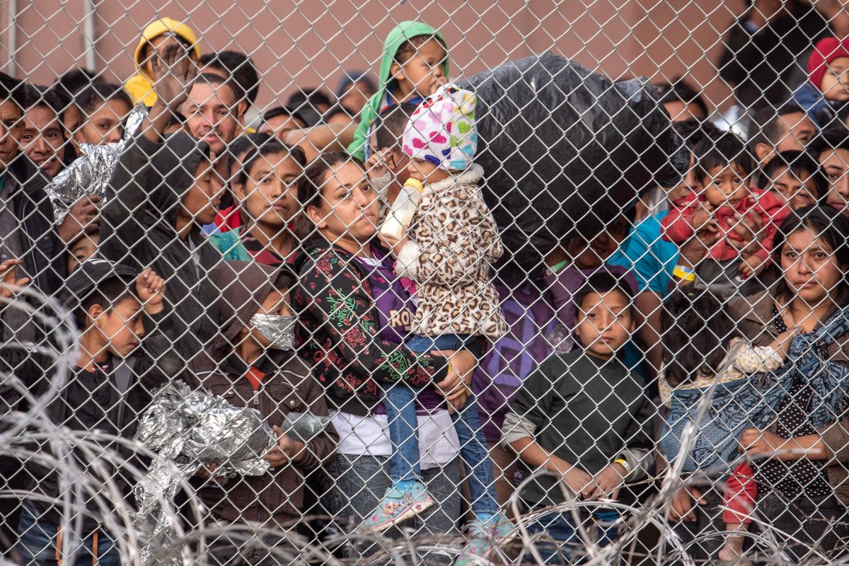Migrants are gathered inside the fence of a makeshift detention center in El Paso on March 27, 2019.   (Sergio Flores/For The Washington Post)