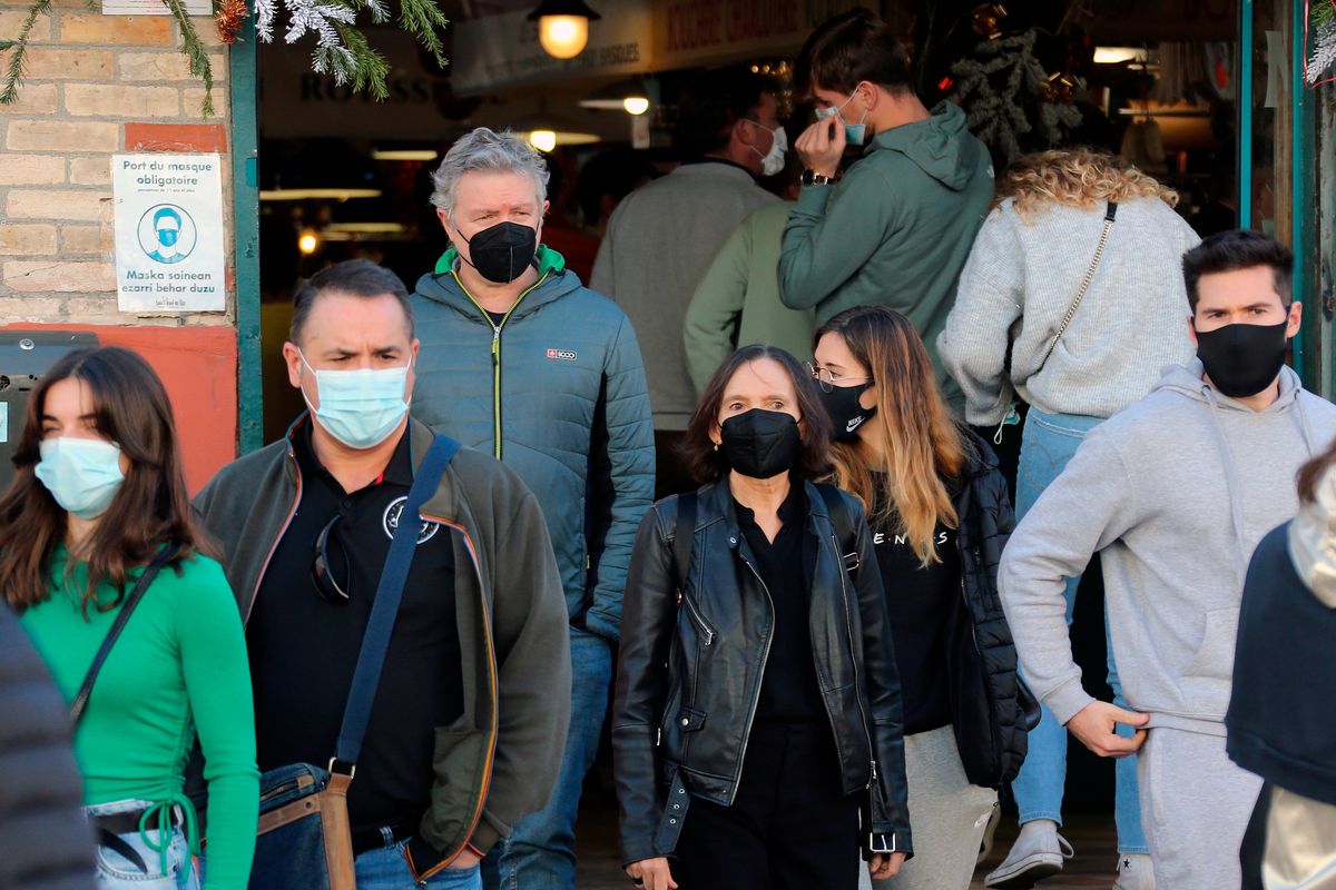 People wearing face mask walk on the street in Saint Jean de Luz, southwestern France, Thursday, Dec.30, 2021. The French government announced this week new measures to fight the spreading of the virus as France reported a record high of 208,000 new infections on Wednesday. Mask-wearing is already mandatory inside shops, public facilities, office buildings and public transports across France. (Bob Edme)