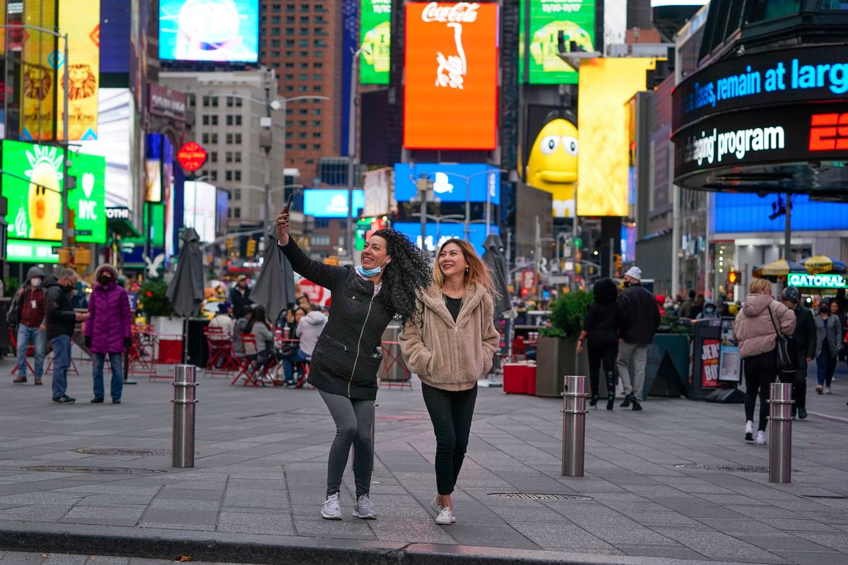 Pedestrians pose for pictures Monday in New York’s Times Square as big crowds begin to return.  (Seth Wenig)