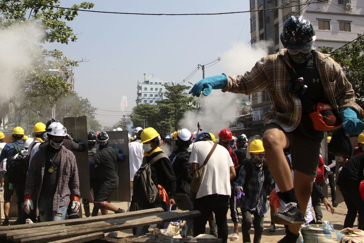 Protesters are dispersed as riot police fired tear gas behind a makeshift barricade in Yangon, Myanmar, Sunday, March 7, 2021. The escalation of violence in Myanmar as authorities crack down on protests against the Feb. 1 coup is raising pressure for more sanctions against the junta, even as countries struggle over how to best sway military leaders inured to global condemnation.  (STR)