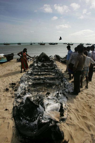 
Sri Lankan villagers look at burned boats in Pesalai  on Sunday. 
 (Associated Press / The Spokesman-Review)