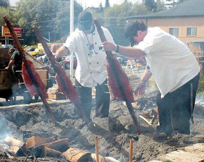 
Chefs from the Mill-Casino Hotel, Chris Foltz, left, and Shawn McCasland, place salmon, at just the right angle, over a hot cedar fire earlier this month in North Bend, Ore. The salmon on the sticks took one hour to cook over the fire while salmon buried in the ground took two hours. 
 (Associated Press / The Spokesman-Review)