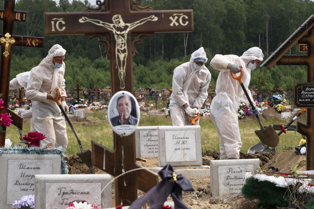 FILE In this file photo taken on Tuesday, June 30, 2020, Grave diggers wearing protective suits bury a COVID-19 victim in the special purpose for coronavirus victims section of a cemetery in Kolpino, outside St.Petersburg, Russia. Russia's updated statistics on coronavirus-linked deaths showed that over 100,000 people with COVID-19 had died in the pandemic by December, a number much higher than previously reported by government officials. According to the data released Monday Dec. 28, 2020, by Russia's state statistics agency, Rosstat, a total of 116,030 people with COVID-19 died in Russia between April and November. The count included cases where the virus was not the main cause of death and where the virus was suspected but not confirmed.  (Dmitri Lovetsky)