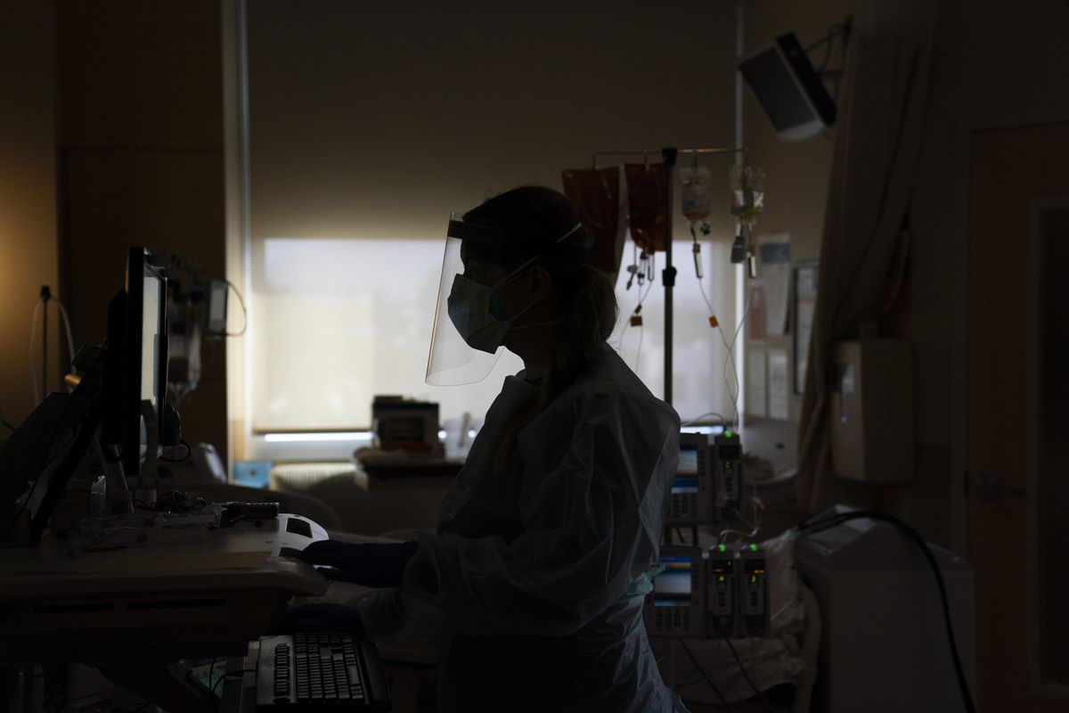 FILE - In this Nov. 19, 2020, file photo, registered nurse Virginia Petersen works on a computer while assisting a COVID-19 patient at Providence Holy Cross Medical Center in the Mission Hills section of Los Angeles. California is desperately searching for nurses, doctors and other medical staff, perhaps from overseas, to meet demands as the coronavirus surge pushes hospitals across the state to the breaking point. With many of the state
