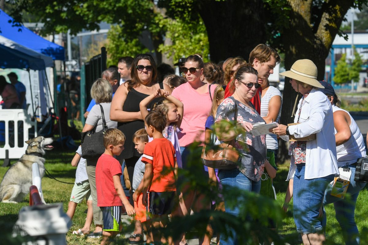 Parents, children and a dog wait in line stretching along Indiana Avenue to choose a backpack at The Salvation ArmyÕs Backpacks for Kids giveaway, Wednesday, Aug. 17, 2022 in Spokane.  (Dan Pelle/The Spokesman-Review)