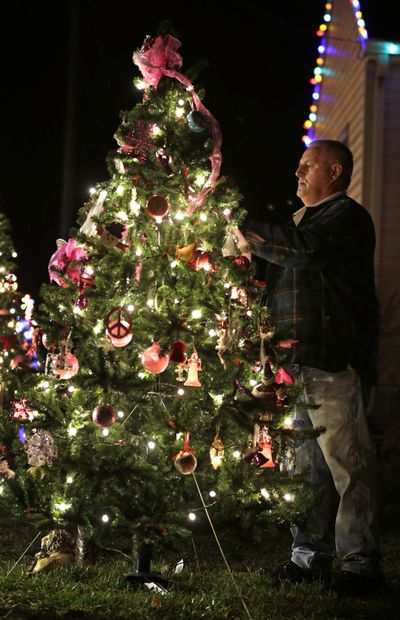Robert Carpenter hangs an angel on a tree during a vigil for missing cousins Lyric Cook, 10, and Elizabeth Collins, 8, who vanished while riding bikes in Evansdale in July, Thursday, Dec. 6, 2012, in Evansdale, Iowa. Authorities announced Thursday they are confident bodies found in an isolated wildlife area are those of the two girls. (Charlie Neibergall / Associated Press)