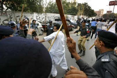 
Riot police with canes beat a journalist with canes Tuesday while they scuffle in Karachi  at a protest against the state of emergency  and crackdown against the press. Associated Press
 (Associated Press / The Spokesman-Review)