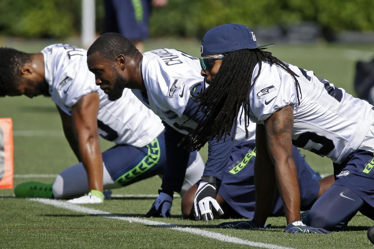 Seattle Seahawks cornerback Richard Sherman, right, stretches with strong safety Kam Chancellor, center, and free safety Earl Thomas, left, during 2017 training camp in Renton, Wash. (Ted S. Warren / AP)