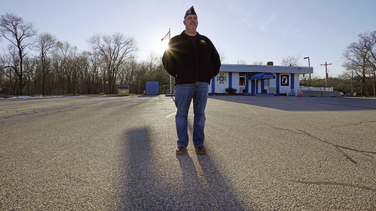 Craig DeOld, commander at Veterans of Foreign War Post #1018, stands in the post’s empty parking lot as the sun sets, Monday, March 15, 2021, in Boston. Local bars and halls run by VFW and American Legion posts have fallen on hard times during the coronavirus pandemic. Organizers say many risk permanent closure after states ordered them, like other bars and halls, to shutter last spring. (Charles Krupa)