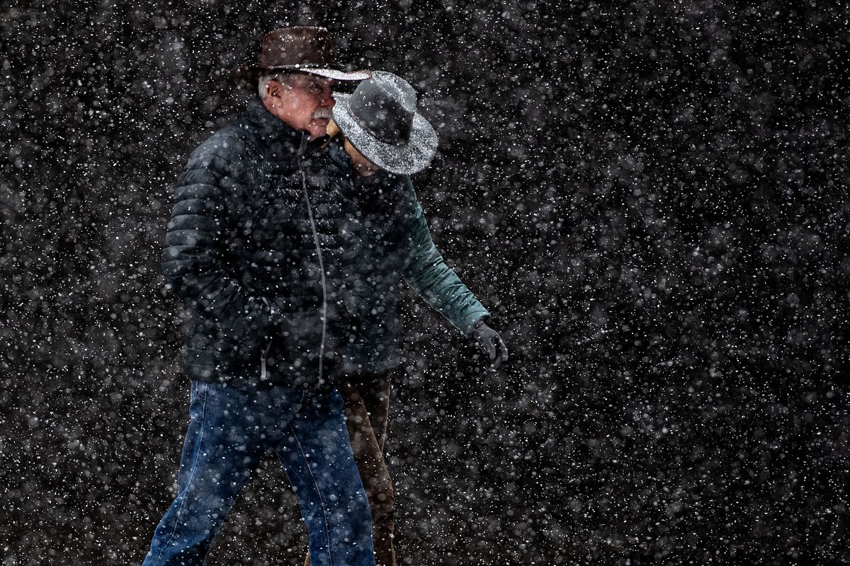 Pedestrians walk through snowflakes Friday on North Post Street in downtown Spokane.  (Colin Mulvany/The Spokesman-Review)