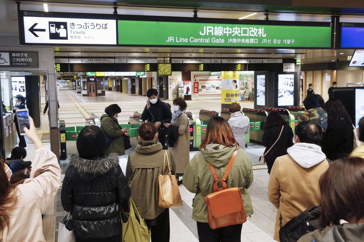 People gather in front of a ticket gate at a station as train services are suspended following an earthquake in Sendai, Miyagi prefecture, Japan Saturday, March 20, 2021. A strong earthquake struck Saturday off northern Japan, shaking buildings even in Tokyo and triggering a tsunami advisory for a part of the northern coast.  (SUB)