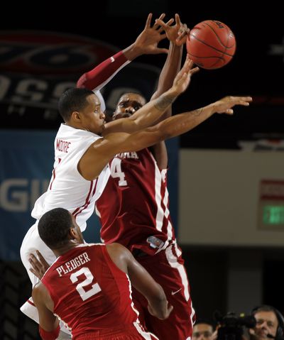 Washington State guard Reggie Moore, left, sneaks a fingertip pass by two Oklahoma defenders. (Associated Press)