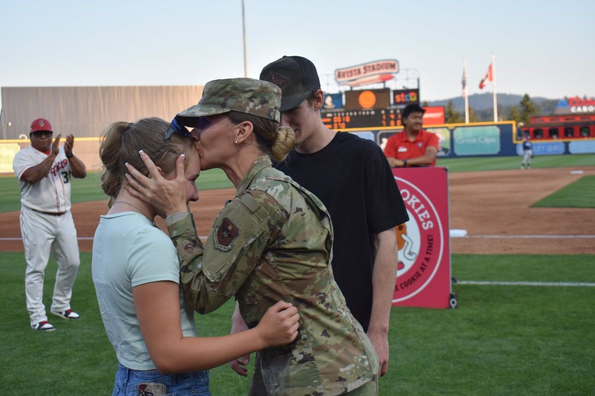 Airman Sierra Burke kisses her daughter Caydence, 13, with son Zach, 18, in the background, after surprising her children with an on-field reunion after graduating from basic training in the Air National Guard at Avista Stadium on Saturday in Spokane.  (Courtesy of Spokane Indians)