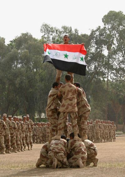 
Iraqi soldiers from the first entirely Sunni basic training class perform beneath an Iraqi flag during their graduation ceremony in Habaniyah on Sunday. 
 (Associated Press / The Spokesman-Review)