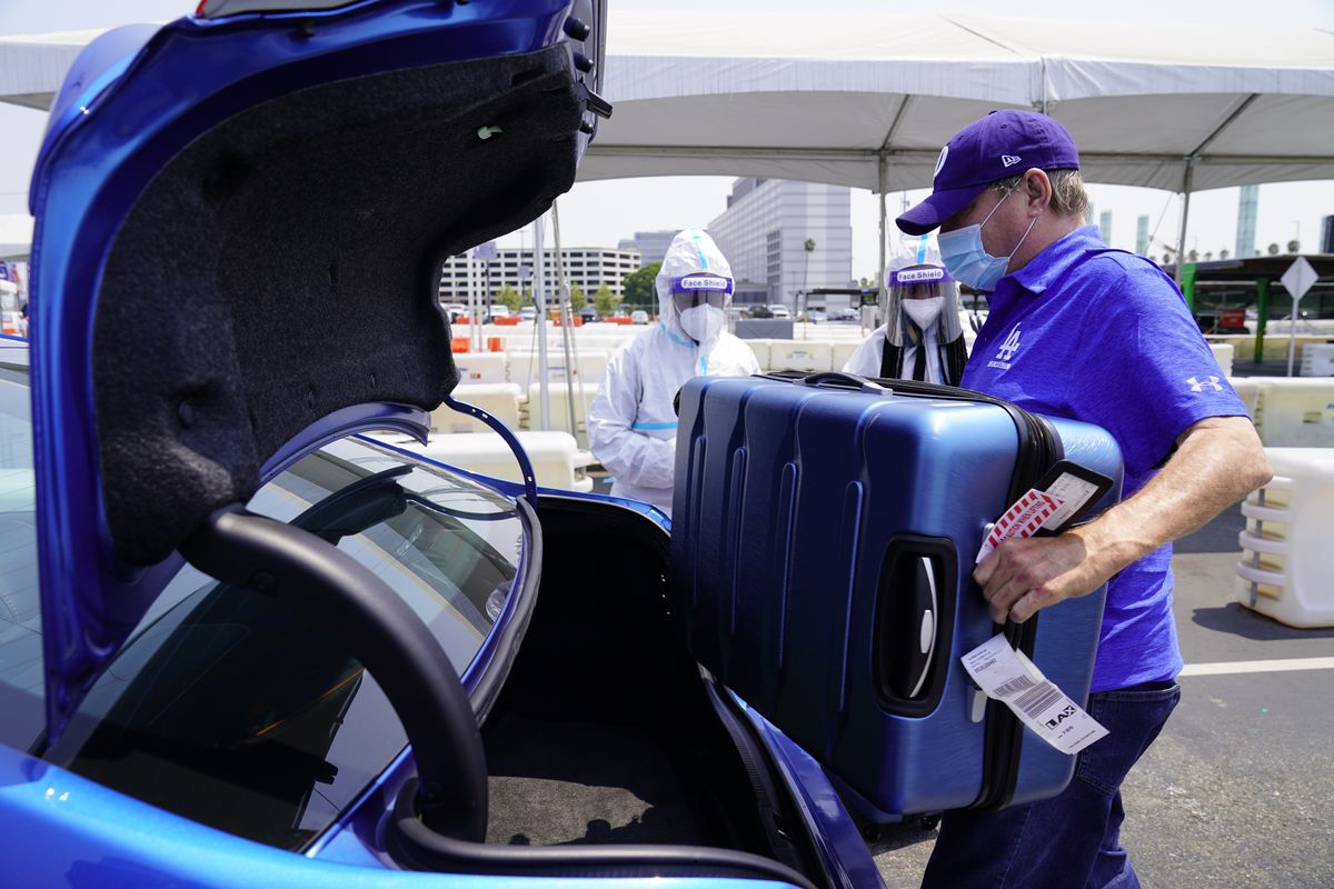 In this Aug. 20, 2020 photo, Uber driver Ralph, only first name given, loads luggage from travelers arriving from New York City at Los Angeles International Airport