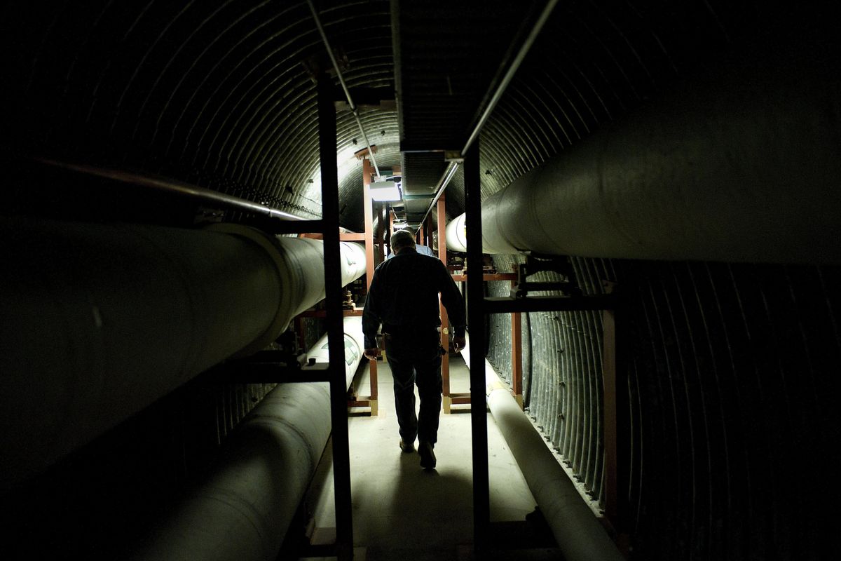 Surrounded by steam pipes used to heat the Spokane County Courthouse, boiler maintenance specialist Dave Endsley walks through a steam tunnel from the courthouse
